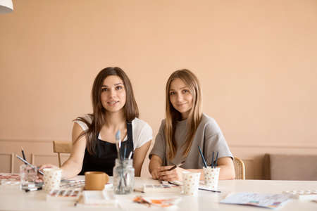 Front view of four beautiful caucasian female at art workshop. A young teacher teaches drawingの写真素材