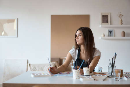 Beautiful Female Artist In Her Studio. Female drawing in album with watercolor paints and paintbrush.の写真素材