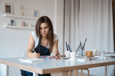 Beautiful Female Artist In Her Studio. Female drawing in album with watercolor paints and paintbrush.の写真素材