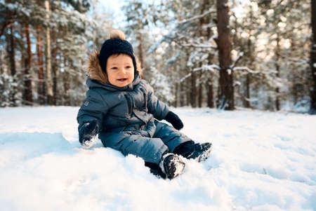 A little boy in the snow. Happy child walking through winter forest.の写真素材