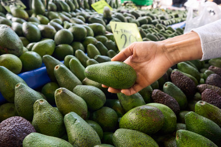 Young Woman Choosing Avocados in Grocery market. Concept of healthy food, bio, vegetarian, diet.