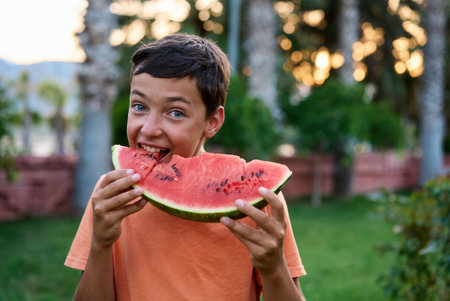 Cute boy eating watermelon outdoors in summer. Healthy eating seasonal berries and fruits.の写真素材