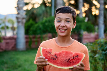 Cute boy eating watermelon outdoors in summer. Healthy eating seasonal berries and fruits.の写真素材
