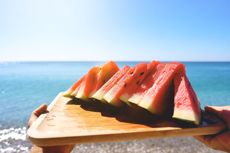 Juicy slices of watermelon on plate. In the background the sea and the beach. Red watermelon, fresh...