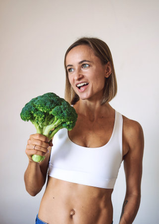 young woman dressed in white t-shirt showing with broccoliの写真素材