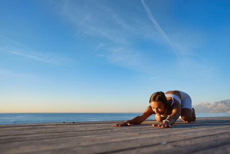 Young sporty woman training in outdoor, working out at animal flow style, making front kick through positionの写真素材