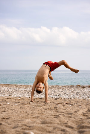 kid does acrobatics on the beachの写真素材