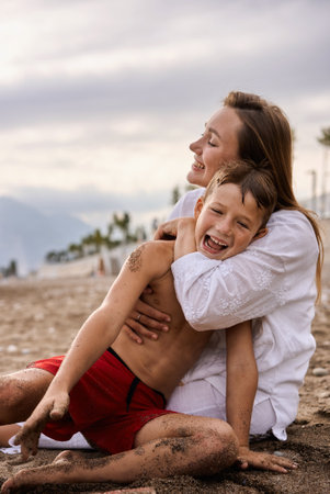 Mom hugs her 6 year old son on the beach.の写真素材