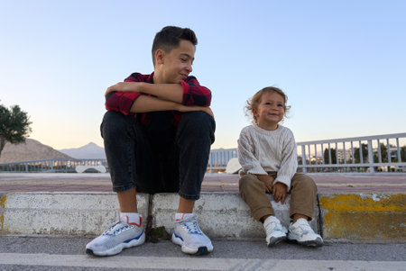 Two brothers sitting outside on a sidewalk and have fun.の写真素材