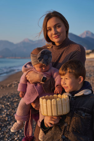 Single parent family celebrate kids bithday at sunrise on the beach with homemade cake. Single mother.の写真素材