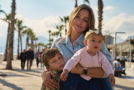 Portrait of smiling mother carrying kids at street.の写真素材