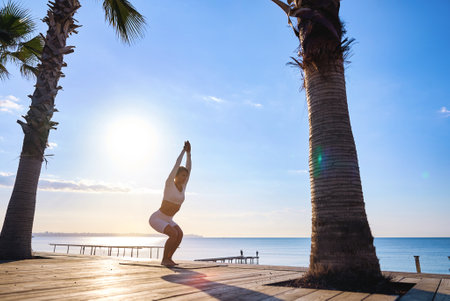 Young healthy woman practicing yoga on the beach at sunrise.の写真素材