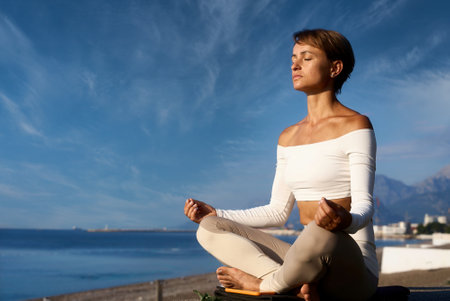 Young fitness woman practicing yoga on the beach, healthy lifestyle concept.の写真素材