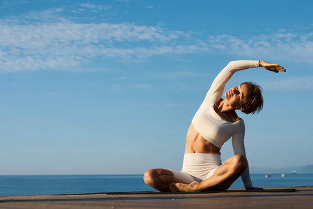 Caucasian woman practicing yoga at seashore of tropic ocean
