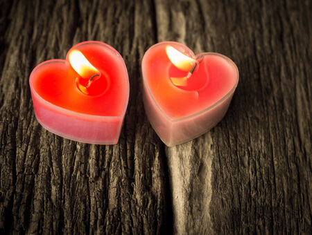 burning heart shaped candles on wood.の写真素材