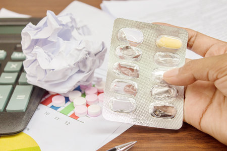 Pills on woman hand with document paper.