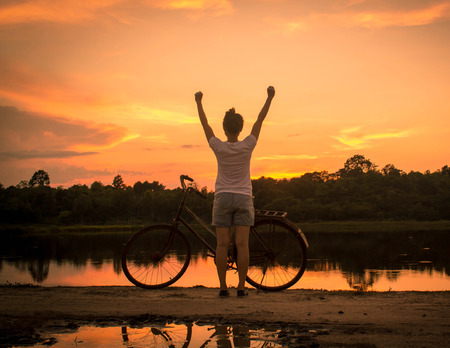 Happy celebrating winning success woman at sunset.の写真素材