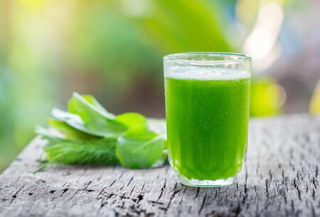 Green vegetable smoothie in a glass on wood.の写真素材