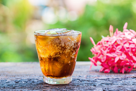 glass of cola with ice cubes on wood table.の写真素材