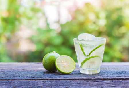 Cold fresh lemonade with lemon on wooden table.