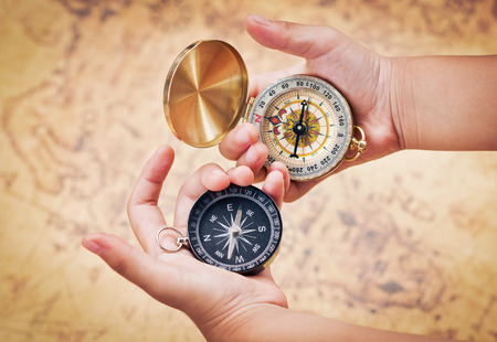 Child hand holding a compass on the map background.の写真素材