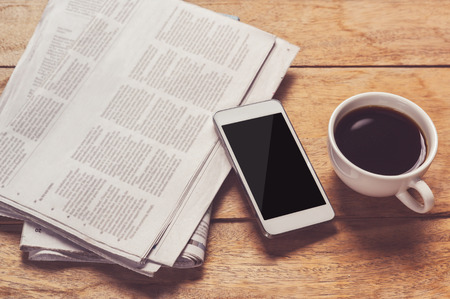 smartphone and cup of coffee with Newspaper in coffee shop.の写真素材