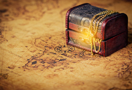 Treasure chest with shinny gold on old map.
