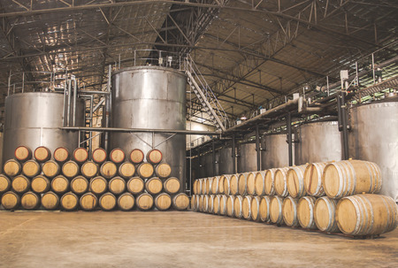 Wine barrels stacked in the wine cellar and large steel tank vessels on a factory,Thailand.の写真素材