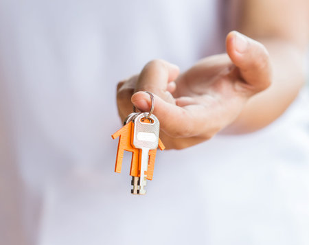 Female hand holding keys with house key,real estate agent.