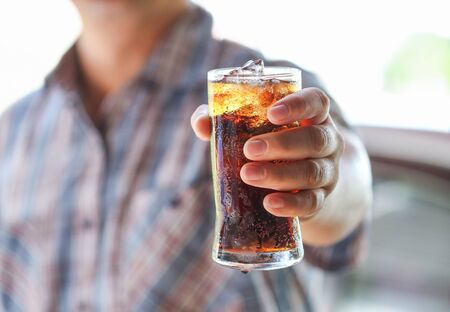 Man hand giving glass of sparkling water,Soft drinks with ice.の写真素材