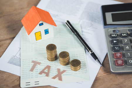 Tax words written on table with calculator,pen, miniature house with money and tax papers.の写真素材