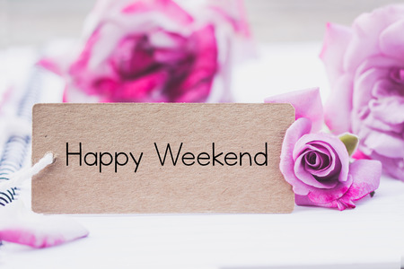 Writing happy weekend on card with rose on notebook.の写真素材
