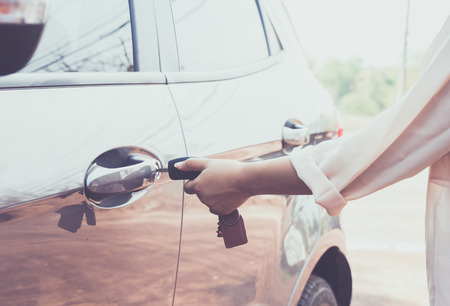 Woman with car key opens the door to a car.の写真素材