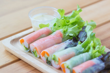 Fresh salad vegetables,noodle spring roll with salad dressing in wooden plate.