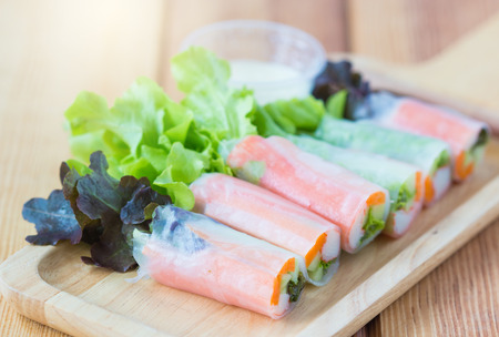 Fresh salad vegetables,noodle spring roll with salad dressing in wooden plate.の写真素材