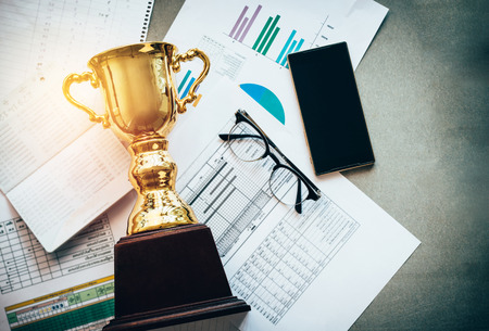 Success concept,a gold trophy with business Information at the desk in office.の写真素材