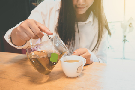 Young Woman pouring tea form teapot into the cup.の写真素材