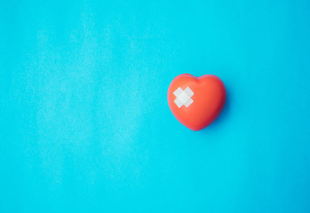 Red heart with bandage on blue background,Healthcare concept.