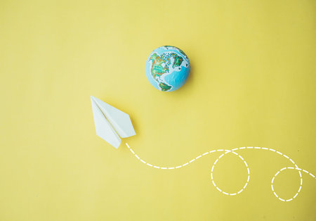 Paper airplane flying  with a white dashed line on a yellow paper background,Travel the world...