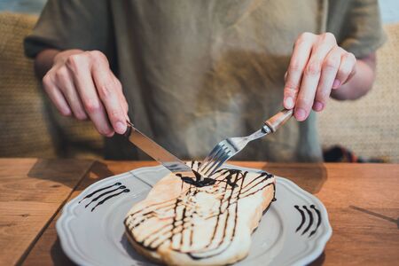 Closeup of woman eating Breaded butter in a cafe.の写真素材