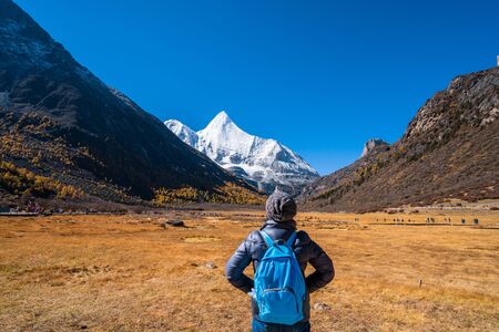 Woman standing with backpack on the Snow Mountain in daocheng yading,Sichuan,China.の写真素材
