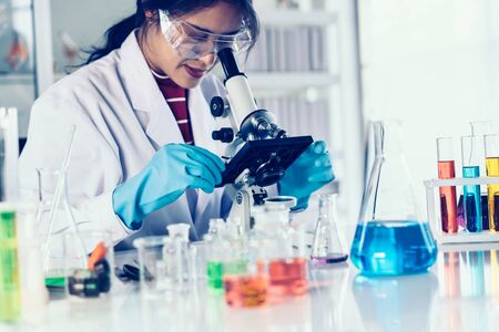 Female scientist looking through microscope in laboratory.の写真素材