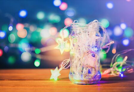 Christmas lights in glass jar on wooden background.の写真素材