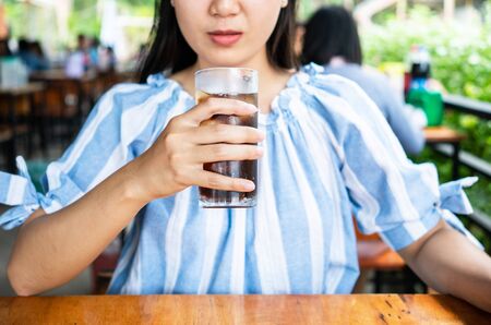 Woman drinking a glass of cola with ice.の写真素材