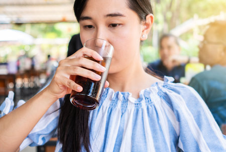 Woman drinking a glass of cola with ice