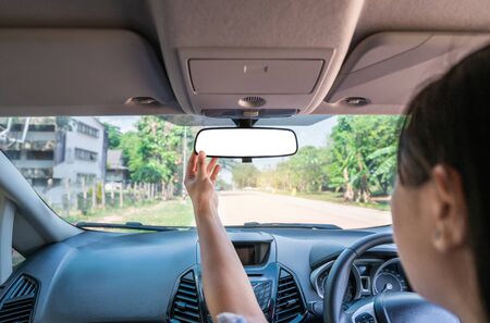 Woman driving a car,Hand adjusting rear view mirror with clipping path.の写真素材