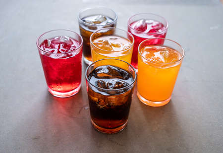 glass of sparkling colorful water with ice cubes on table.の写真素材