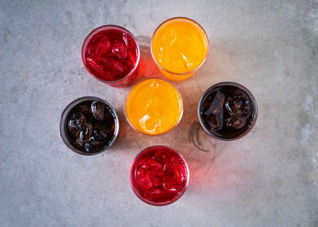 glass of sparkling colorful water with ice cubes on table.の写真素材