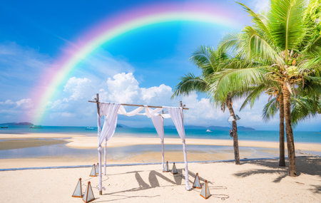 Colorful rainbow over the sea with wedding arch on the beach,tropical outdoor wedding.の写真素材