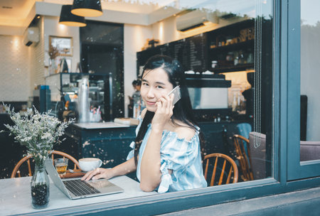 Asian woman smiling using smart phone in the coffee shop.の写真素材
